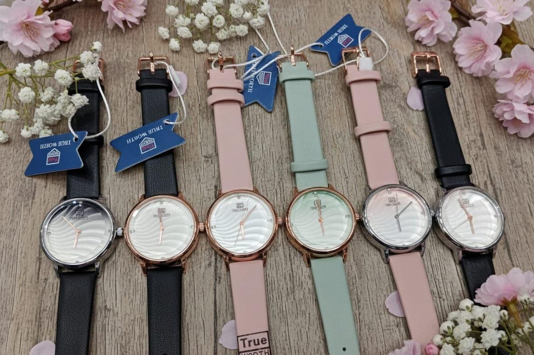 collection of "True Worth" women's analog watches with leather-look straps in various colors, including black, pink, and mint green-